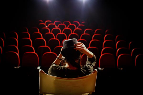 person sitting on stage in front of empty audience seats